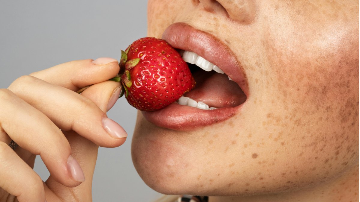 Woman holding a strawberry to her lips representing self love rituals for women