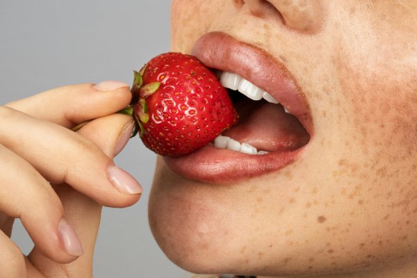 Woman holding a strawberry to her lips representing self love rituals for women