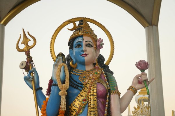 Ardhanarisvara statue depicting the union of masculine and feminine divine energy, holding a trident and lotus flower